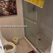 bathroom featuring tile patterned flooring, an enclosed shower, and toilet