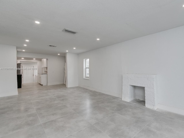 unfurnished living room with a brick fireplace and a textured ceiling