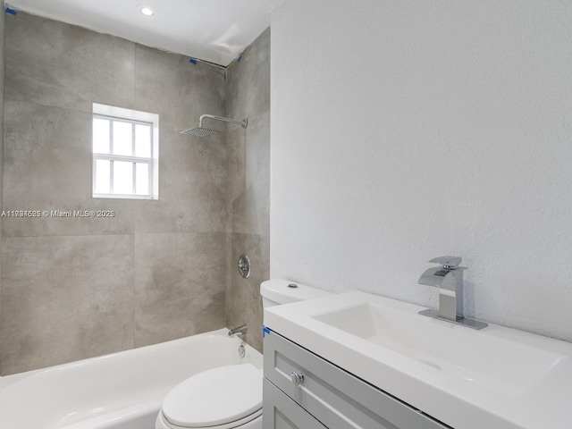 full bathroom featuring tiled shower / bath combo, vanity, and toilet