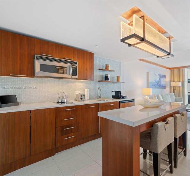 kitchen featuring a kitchen bar, sink, light tile patterned floors, a kitchen island, and decorative backsplash