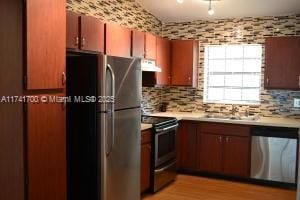 kitchen featuring appliances with stainless steel finishes, sink, light hardwood / wood-style flooring, and backsplash