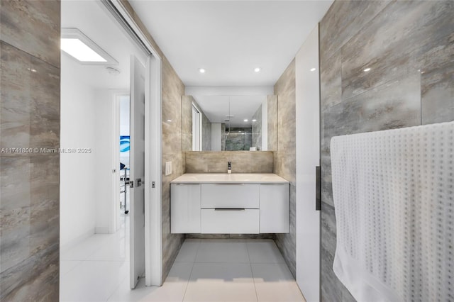 bathroom with vanity, a shower with door, tile patterned flooring, and tile walls