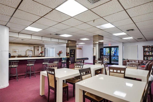 dining room with bar area, carpet flooring, and a drop ceiling