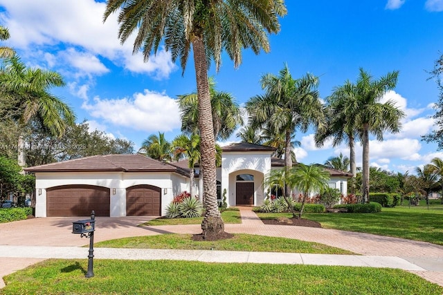 mediterranean / spanish-style house with a garage and a front lawn