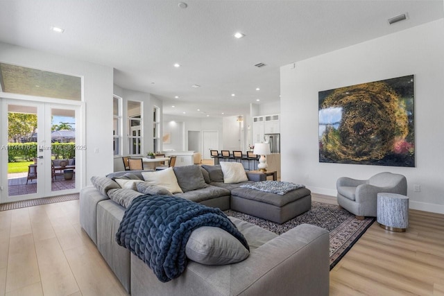 living room with a textured ceiling, light hardwood / wood-style floors, and french doors