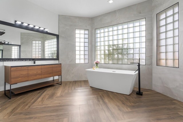 bathroom featuring parquet floors, vanity, and a bath