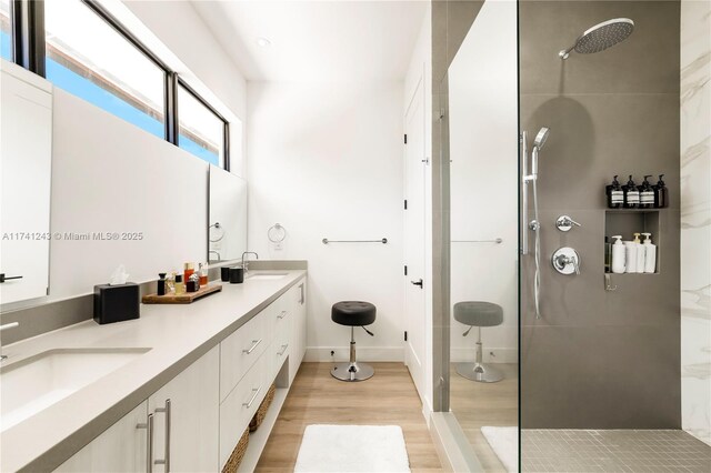 bathroom with hardwood / wood-style flooring, vanity, and tiled shower