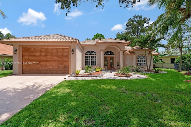 mediterranean / spanish-style home featuring stucco siding, a front lawn, driveway, a tile roof, and an attached garage