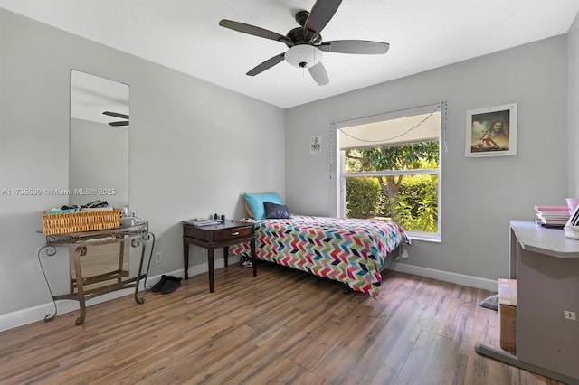 bedroom featuring dark wood-style floors, a ceiling fan, and baseboards