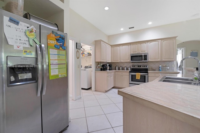 kitchen featuring appliances with stainless steel finishes, light countertops, a sink, and light brown cabinets