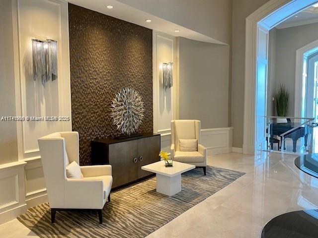 living area featuring an accent wall, recessed lighting, crown molding, and baseboards