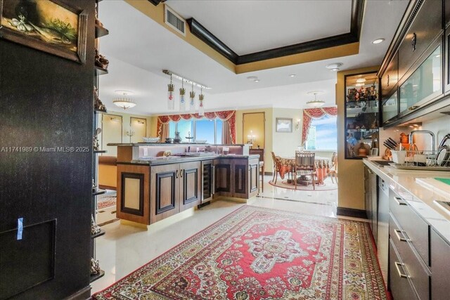 kitchen featuring beverage cooler, visible vents, baseboards, a raised ceiling, and crown molding