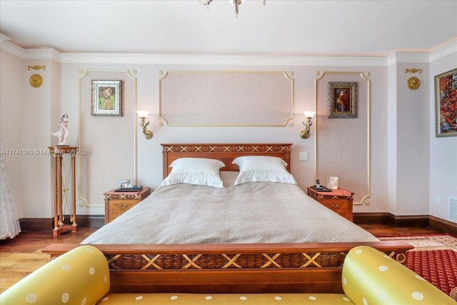 bedroom with ornamental molding, visible vents, baseboards, and wood finished floors