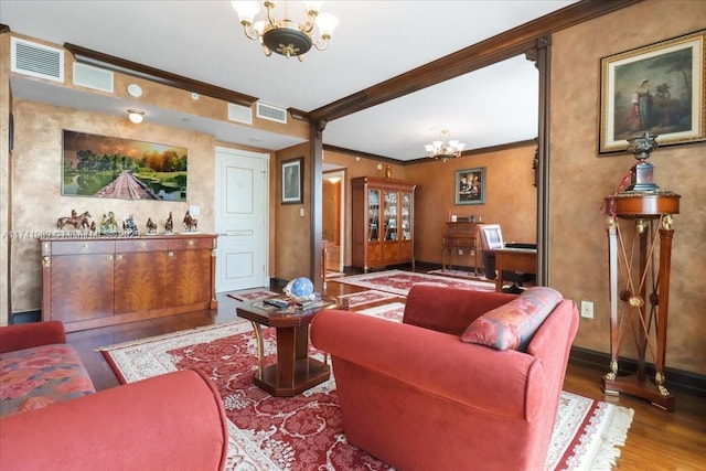 living area with ornamental molding, wood finished floors, visible vents, and an inviting chandelier