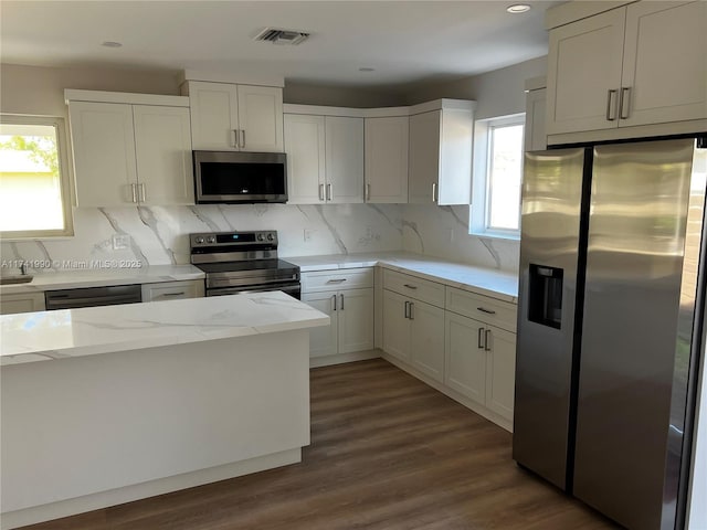 kitchen featuring stainless steel appliances, dark wood-type flooring, white cabinets, and backsplash