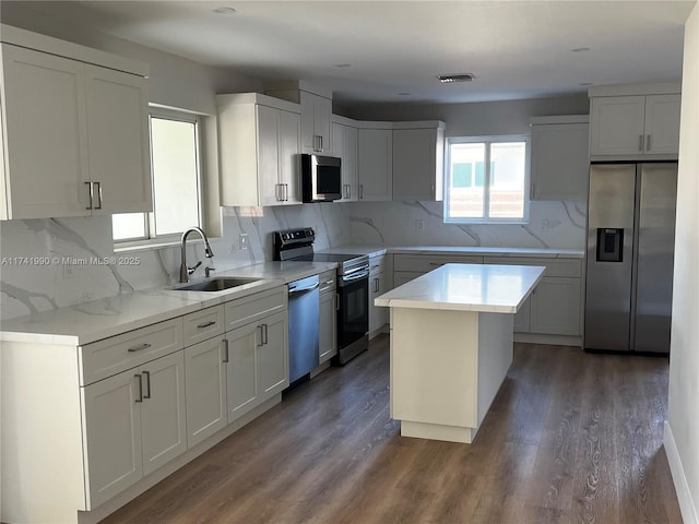 kitchen featuring sink, stainless steel appliances, a center island, and white cabinets