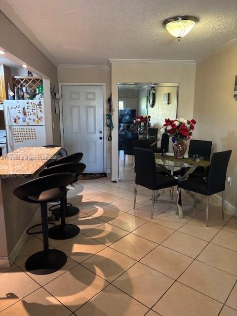 tiled dining room with ornamental molding and a textured ceiling