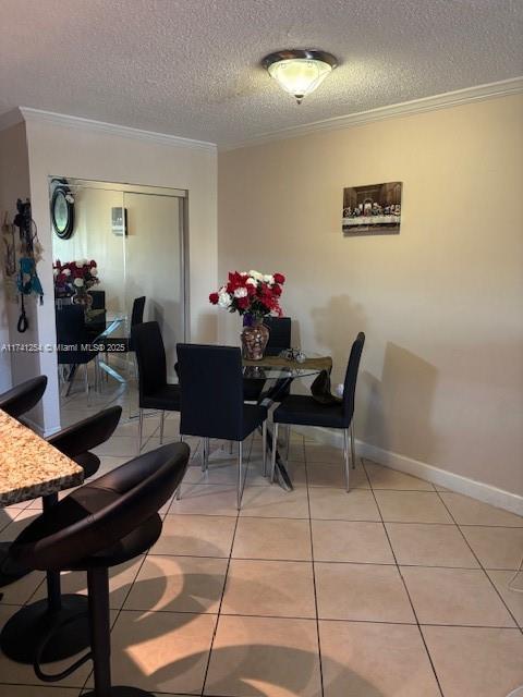 tiled dining room with crown molding and a textured ceiling