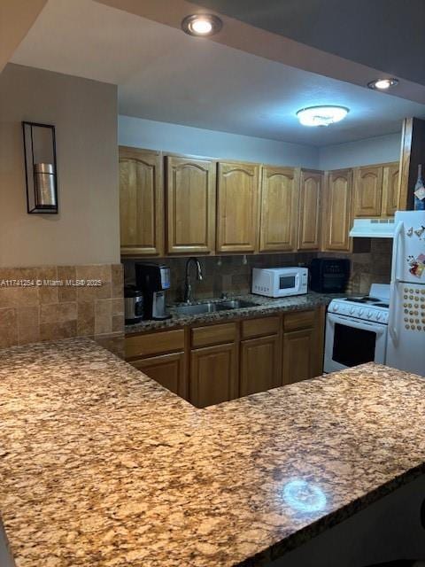 kitchen featuring white appliances, light stone countertops, sink, and decorative backsplash