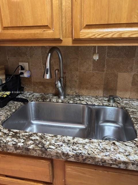 room details with sink, dark stone countertops, and decorative backsplash