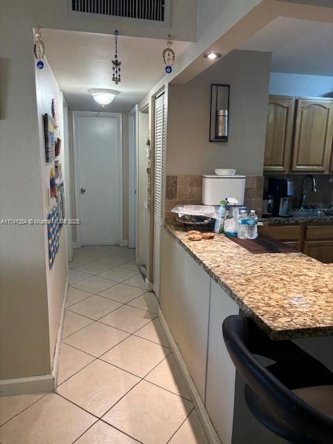 kitchen with sink, light tile patterned floors, dark stone countertops, tasteful backsplash, and decorative light fixtures