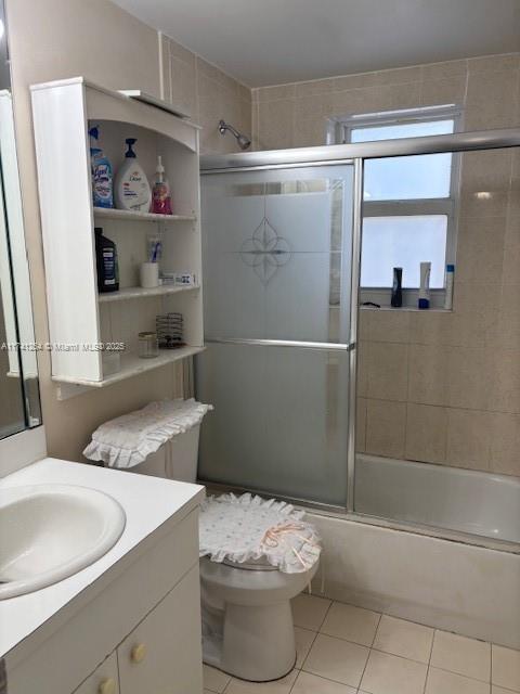 full bathroom featuring tile patterned flooring, vanity, enclosed tub / shower combo, and toilet