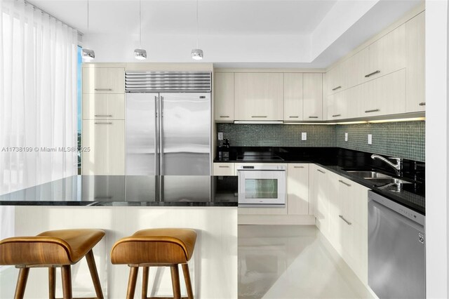 kitchen with stainless steel appliances, a breakfast bar, sink, and decorative backsplash