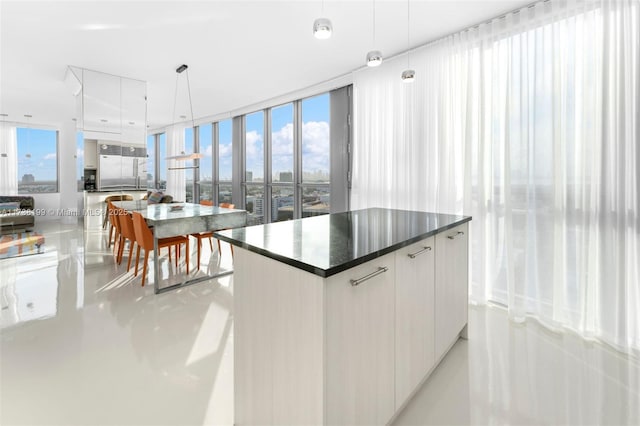 kitchen featuring white cabinetry, hanging light fixtures, built in fridge, a kitchen island, and a wall of windows