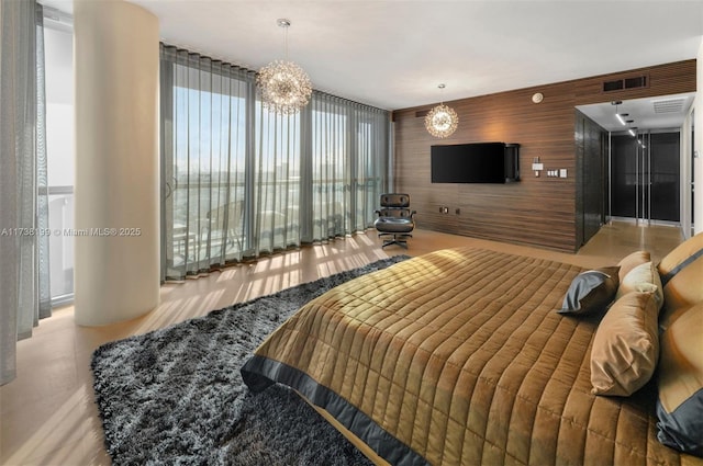 bedroom with wooden walls, a chandelier, and a wall of windows