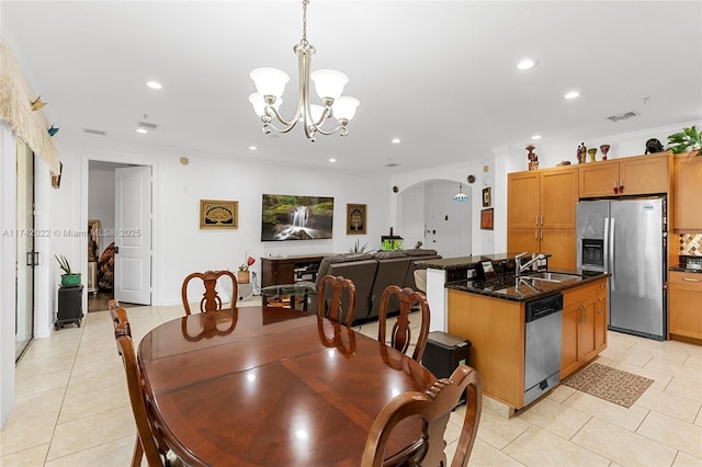 dining area with crown molding, sink, light tile patterned floors, and a notable chandelier