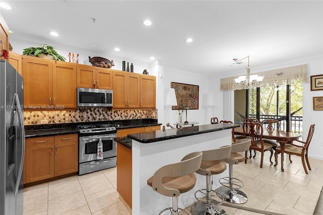 kitchen with pendant lighting, appliances with stainless steel finishes, dark stone countertops, a kitchen breakfast bar, and a center island