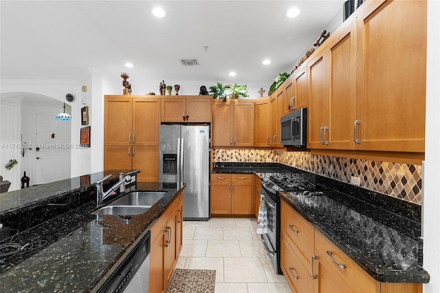 kitchen with sink, light tile patterned floors, stainless steel appliances, decorative backsplash, and dark stone counters