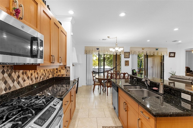 kitchen featuring dark stone countertops, pendant lighting, a kitchen island with sink, and appliances with stainless steel finishes