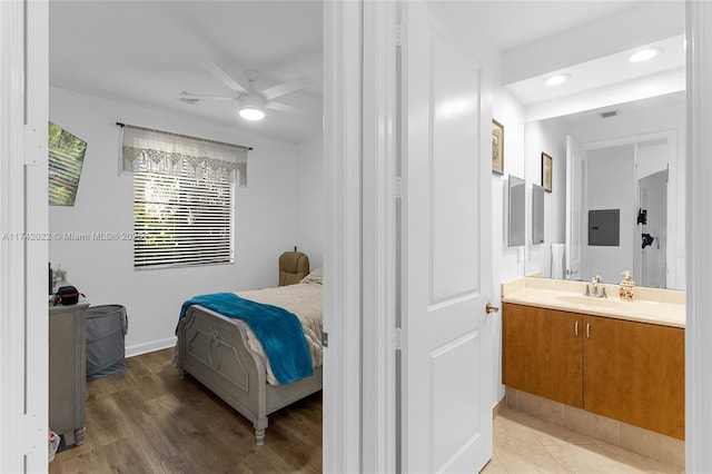 bedroom featuring connected bathroom, sink, hardwood / wood-style floors, and ceiling fan