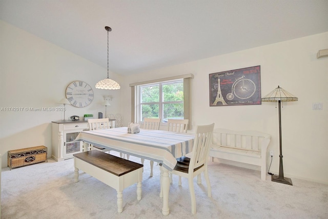 carpeted dining space featuring vaulted ceiling