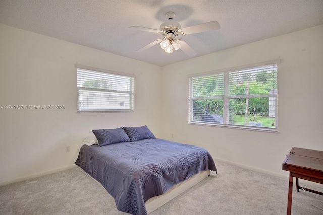 bedroom with light colored carpet, multiple windows, and a textured ceiling