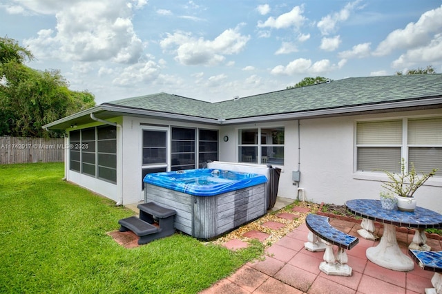 rear view of property with a hot tub, a sunroom, and a lawn