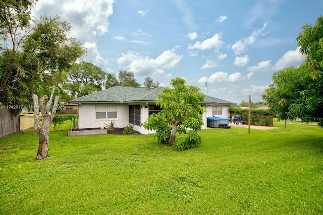 rear view of house with a yard and a jacuzzi