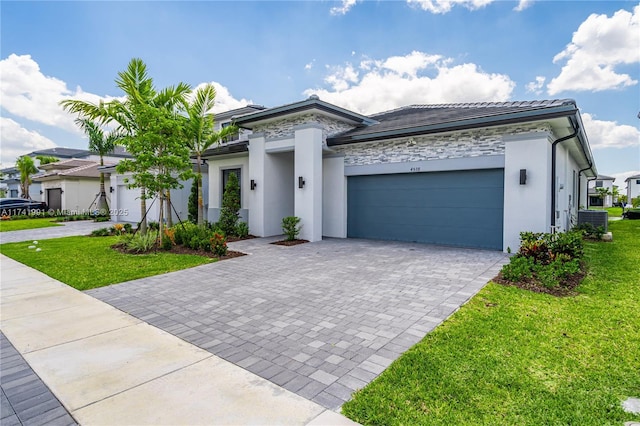 view of front of home featuring a garage, a front lawn, and central air condition unit