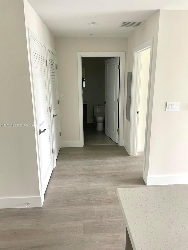 corridor featuring electric panel and light hardwood / wood-style flooring