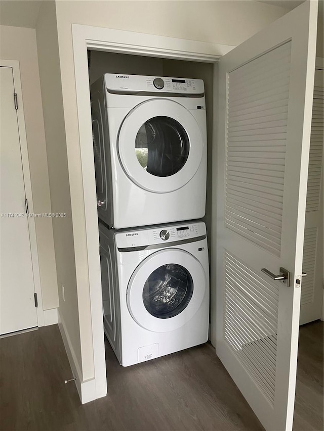 washroom featuring stacked washer and clothes dryer and dark wood-type flooring