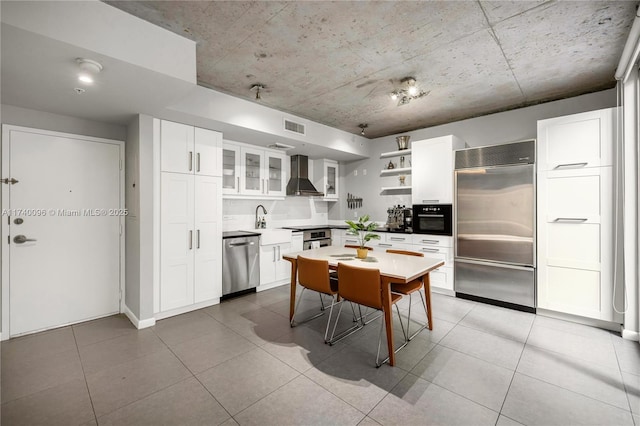 kitchen with white cabinetry, stainless steel appliances, wall chimney exhaust hood, and light tile patterned flooring