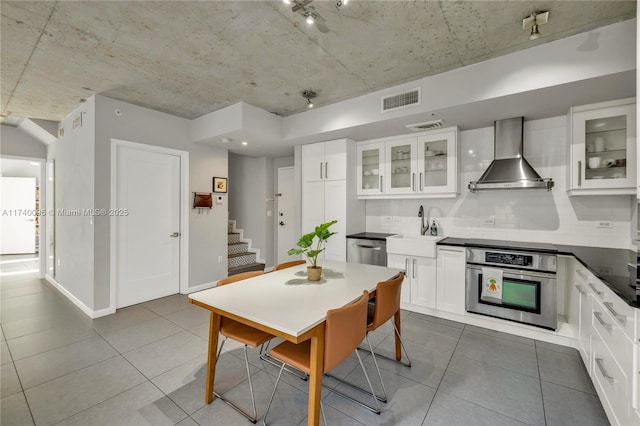 kitchen with white cabinetry, wall chimney range hood, and appliances with stainless steel finishes