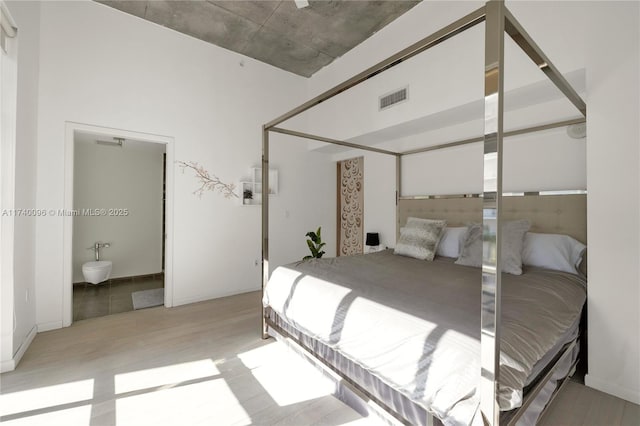 bedroom with ensuite bath and light hardwood / wood-style floors