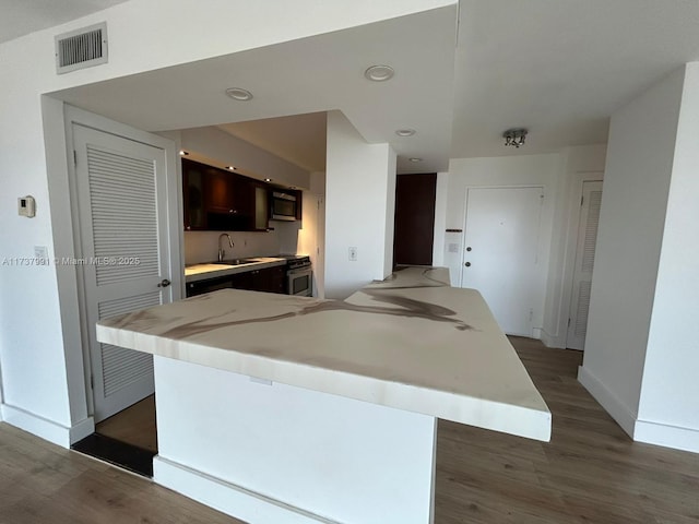 kitchen with sink, dark brown cabinets, dark wood-type flooring, and a center island