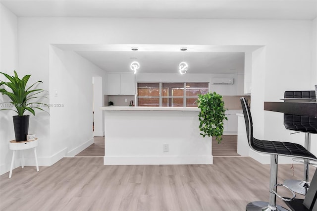 658 SW 1st Ct, Boynton Beach, FL 33426 - kitchen with white cabinets, light wood-type flooring, light countertops, pendant lighting, and an AC wall unit