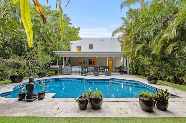 view of swimming pool with grilling area, exterior bar, and a patio area