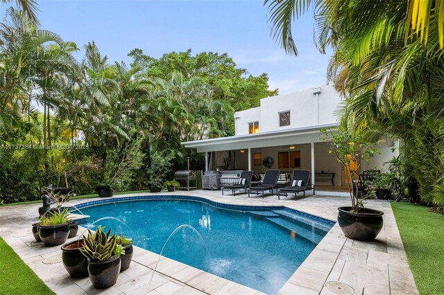 view of pool with pool water feature, ceiling fan, and a patio area