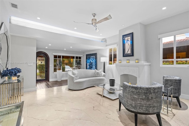 living room featuring ceiling fan and a high end fireplace