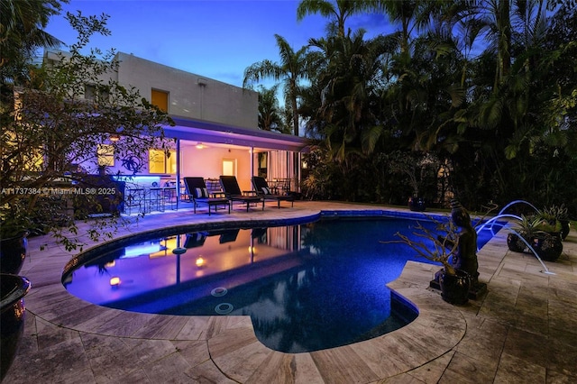 pool at dusk featuring a hot tub and a patio